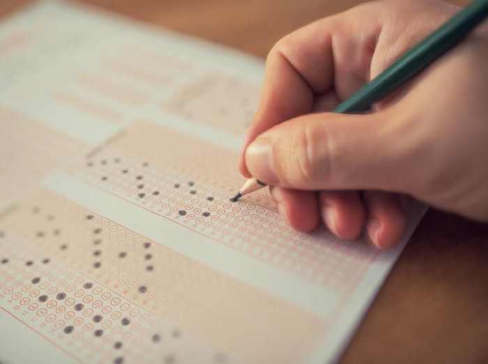 Education school test concept : Hands student holding pencil for testing exams writing answer sheet or exercise for taking fill in admission exam multiple carbon paper computer at university classroom