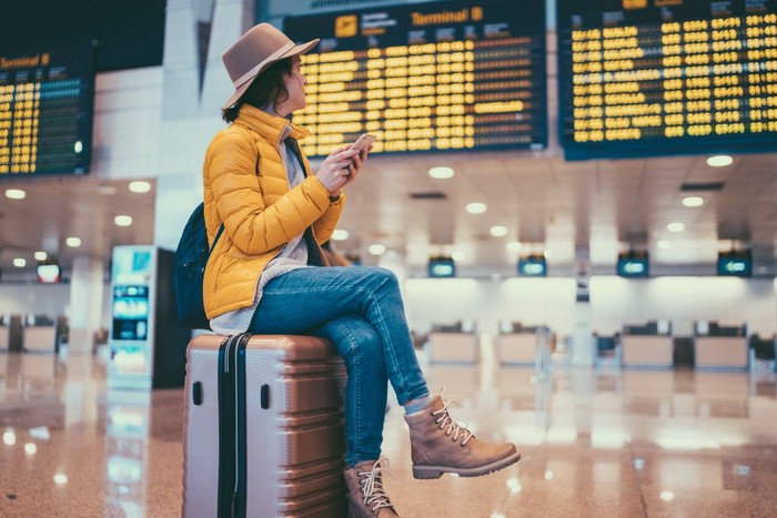 Mother picking backpack from security counter while standing by daughters. Family is with luggage at airport terminal. They are going on vacation.