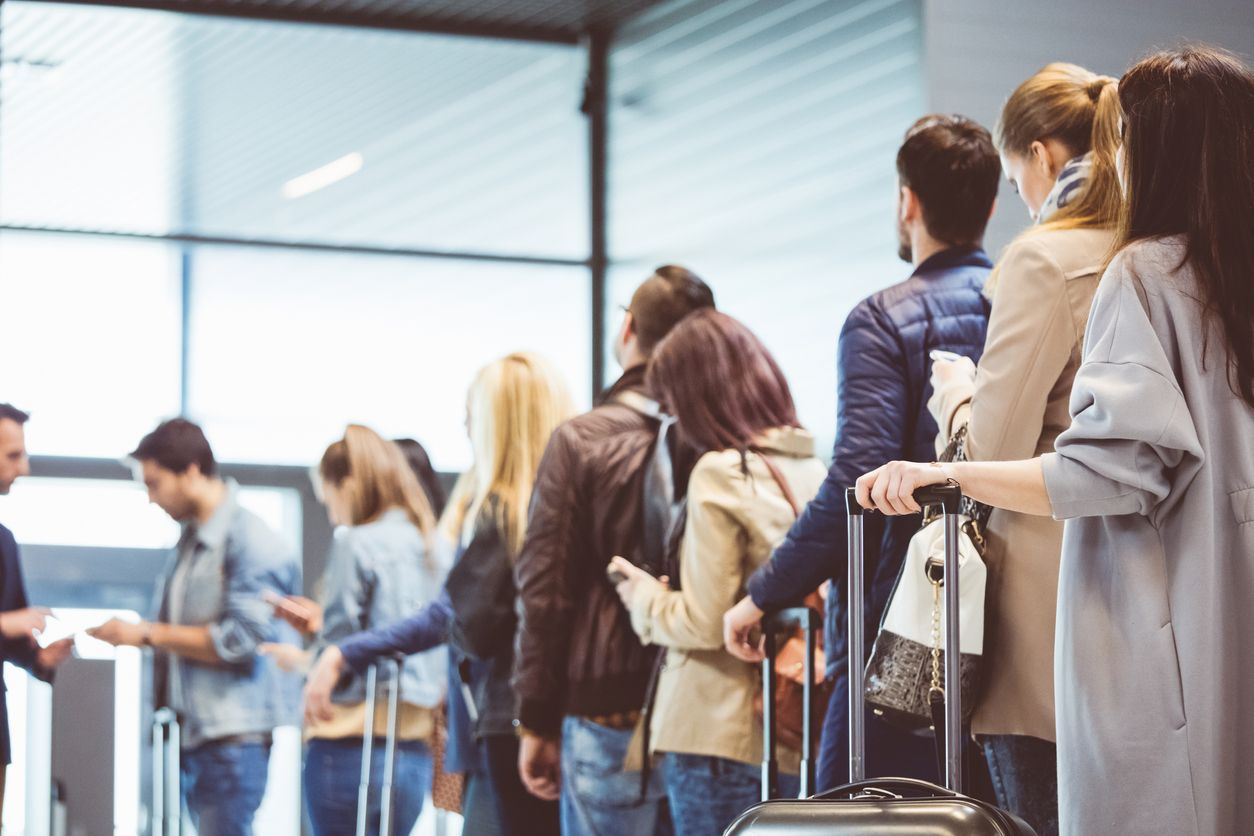Mother picking backpack from security counter while standing by daughters. Family is with luggage at airport terminal. They are going on vacation.