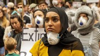 Warga nampak menggantungkan masker di leher mereka saat mengikuti aksi demonstrasi karena memburuknya kualitas udara di Kota Sydney imbas kebakaran hutan.