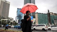 Seorang warga mengenakan payung saat beraktivitas di luar ruangan untuk melindungi diri agar tak basah saat hujan mengguyur wilayah Jakarta, Kamis (12/12/2019).