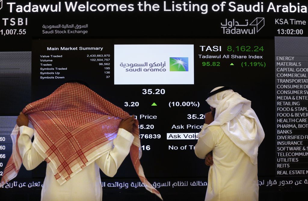 A Saudi stock market official smiles as he watches the stock market screen displaying Saudi Arabia's state-owned oil company Aramco after the debut of Aramco's initial public offering (IPO) on the Riyadh's stock market in Riyadh, Saudi Arabia, Wednesday, Dec. 11, 2019. (AP Photo/Amr Nabil)