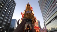 Seorang pengunjung terlihat mengabadikan lanskap pohon Natal di kawasan Cheonggye, Seoul, Korea Selatan. AP Photo/Ahn Young-joon.