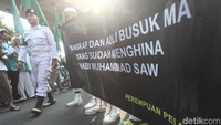 Di antara poster yang dibawa, tampak ada yang bertulisan Penghina Nabi Muhammad SAW Harus Dihukum.