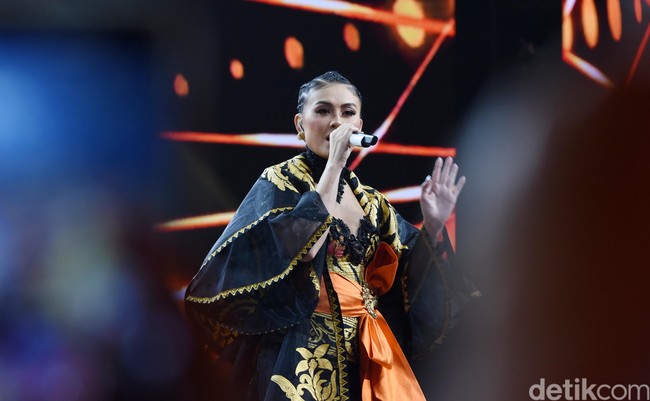 Dengan bahu yang terbuka, atasan tersebut sukses mempertegas aura seksi Agnez Mo. Untuk menyempurnakan gayanya, ia memakai statement necklace hitam berikut boot kulit setinggi lutut. (Foto: Noel/detikFoto)