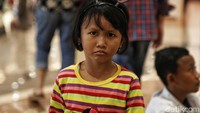 Anak ini ikut menonton bersama orangtuanya.