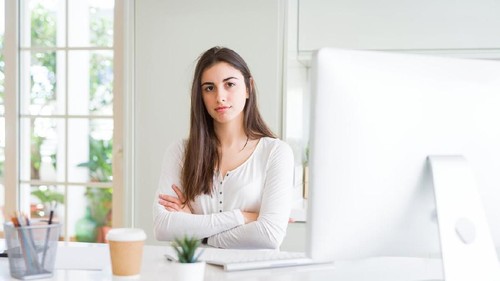 Beautiful young woman working using computer skeptic and nervous, disapproving expression on face with crossed arms. Negative person.