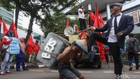 Seorang peserta aksi dengan topi camping tani terlihat memikul sebuah batu bertuliskan BPJS.