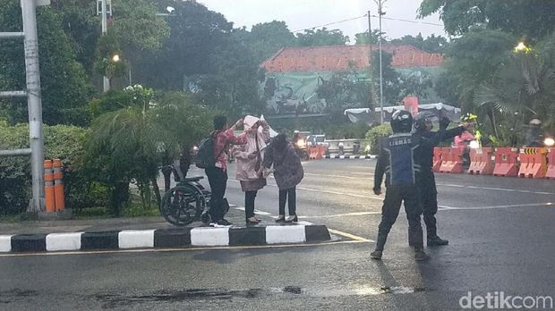 Saat Risma mengenakan jas hujan