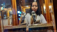 Seorang pengunjung melihat jenglot berbadan ular yang dipamerkan.