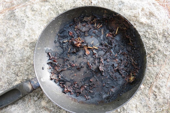Woman trying to clean burnt pan with chemical cleaners.