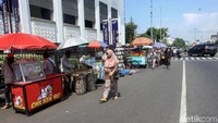 Seorang pejalan kaki melintas di samping PKL yang menggelar lapak dagangan mereka di samping Museum Mandiri, Jakarta, Rabu (18/12/2019).
