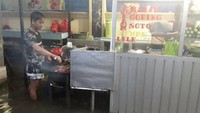 Banjir membuat pria penjual makanan ini sampai menggulung celananya. Namun, aktivitas membakar makanan untuk pelanggan tetap jalan terus. Foto: Istimewa