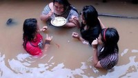 Di tengah-tengah banjir, wanita itu malah sibuk makan. Nikmatinya makan sambil ditemani dengan ketiga temannya yang juga ikut terendam banjir. Foto: Istimewa