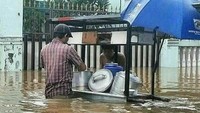 Lihat meski air banjir sudah menenggelamkan sebagian gerobak, tetapi kedua orang ini masih santai bertransaksi beli makanan. Kayaknya lapar banget nih. Foto: Istimewa