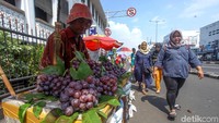 Seorang PKL menjajakan buah-buahan di samping Museum Mandiri, Jakarta.