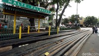 Beberapa warga tampak sedang menunggu bus di sebagian bidang jalan.