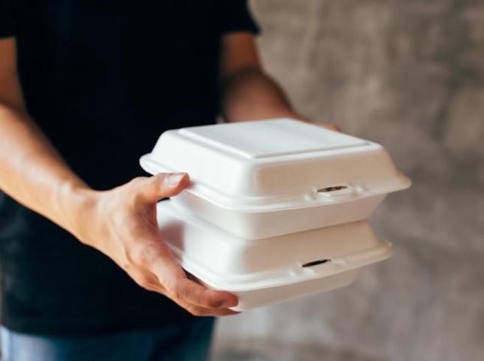 Close-up of delivery man handing a slack of foam lunch box - Foam box is toxic plastic waste. It can be used for recycling and environment saving concept