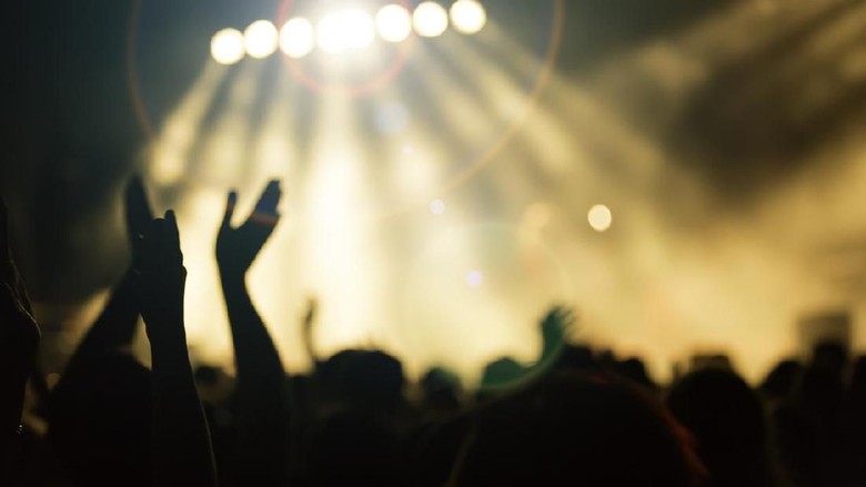 Konser crowd of young people enjoying a music concert with colorful stage lights