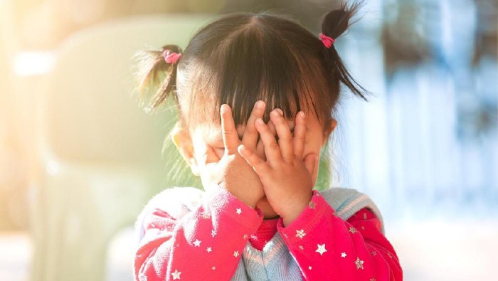 Cute asian baby girl closing her face and playing peekaboo or hide and seek with fun