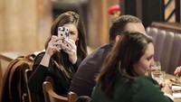 Seorang warga bahkan mengabadikan momen saat menyaksikan voting pemakzulan Trump oleh DPR lewat telepon genggamnya. Julio Cortez/AP Photo.