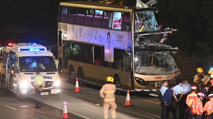 Firefighters, medics and police gather near a double-decker bus after a crash in Kwu Tung in Hong Kong on December 18, 2019. - Six people were killed and dozens injured in Hong Kong on December 18 when a double-decker bus smashed into a tree, police said. (Photo by Philip FONG / AFP)