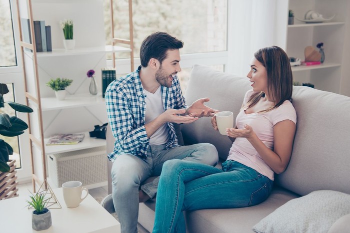 zodiak Profile side view portrait of two nice lovely attractive sweet cheerful cheery people husband wife sitting on divan discussing news in white light interior room