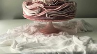Didominasi warna merah muda yang cantik, kue ini dihiasi bunga putih di sekelilingnya. Kue ini memiliki layer yang penuh. Tampil artistik, kue ini bergaya taman bunga yang cantik. Foto: Instagram @albenacakedesign