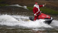 Begini aksi Santa Claus ala Brasil yang asyik mengendarai jet ski di pantai Copacabana, Rio de Janeiro.