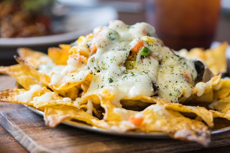 A plate of delicious tortilla nachos with melted cheese sauce and dressing. Food background.
