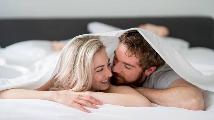 596376444 Loving young couple in bed looking very affectionate towards each other - relationship concepts