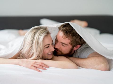 Loving young couple in bed looking very affectionate towards each other - relationship concepts