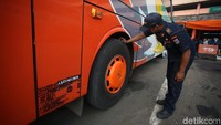 Seorang petugas Dishub DKI Jakarta memeriksa bagian roda bus di kawasan Terminal Kampung Rambutan, Jakarta.