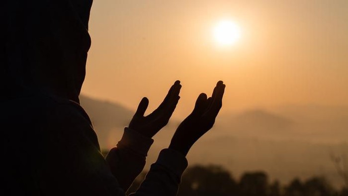 Silhouette of young  human hands open palm up worship and praying to god  at sunrise, Christian Religion concept background.