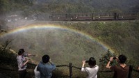 Sejumlah pengunjung mengabadikan momen munculnya pelangi di kawasan China. Kevin Frayer/Getty Images.