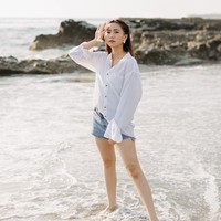 Gaya kasual Shania saat bersantai di pantai: rok pendek denim dan kemeja putih longgar. (Foto: Instagram/@shanju)