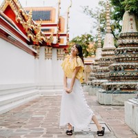 Gaya liburan Shania di Bangkok. Ia mengandalkan blus ruffle dan rok putih panjang maxi, berikut sliders hitam beraksen pita. Cute! (Foto: Instagram/@shanju)