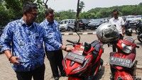 Petugas menempeli stiker pada motor yang ketahuan menunggak pajak di IRTI Monas, Jakarta, Senin (23/12/2019).