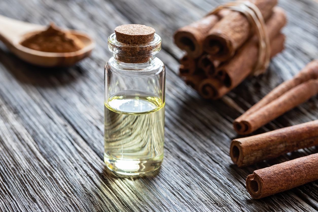 A bottle of essential oil with cinnamon bark on a rustic background