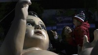 Seorang ibu memperlihatkan dari dekat patung bayi yesus raksasa tersebut.