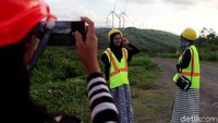 Mengambil foto dengan latar belakang kincir angin dan pemandangan pegunungan menjadi hal yang tidak ingin dilewatkan.