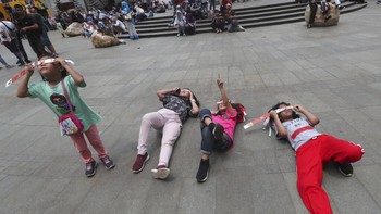 Sembari tiduran menyaksikan saat-saat Bulan menutupi Matahari. Foto: AP Photo/Tatan Syuflana