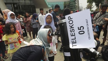 Pengunjung Planetarium Jakarta yang mencoba melihat Gerhana Matahari lewat teleskop yang disediakan. Foto: AP Photo/Tatan Syuflana
