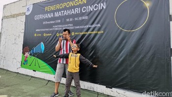 Pengunjung tampak bersuka ria dan menikmati momen Gerhana Matahari Cincin. Misalnya saja ayah dan anak ini, kapan lagi bisa lihat gerhana kan? (detikINET/Aisyah Kamaliah)