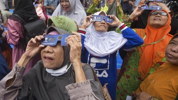 Ibu-ibu di Medan menyaksikan Gerhana Matahari menggunakan kacamata yang disediakan fakultas Astronomi Universitas Muhammadiah Sumatera Utara. Foto: AP Photo/Binsar Bakkara