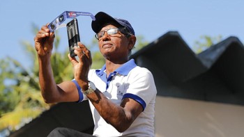 Seorang pria tengah mengabadikan Gerhana Matahari lewat ponselnya. Foto: AP Photo/Eranga Jayawardena