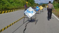Polisi memasang papan peringatan di jalan raya yang mengalami retak di perbatasan Entikong, Kabupaten Sanggau, Kalimantan Barat, Kamis (26/12/2019). ANTARA FOTO/Agus Alfian.