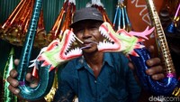 Seorang pedagang menunjukkan terompet yang memiliki bentuk seperti naga di salah satu ujung terompetnya.