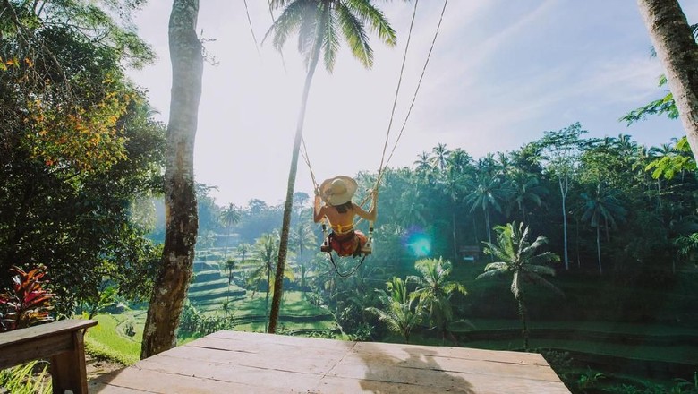 Beautiful girl visiting the Bali rice fields in tegalalang, ubud. Using a swing over the jungle. Concept about people, wanderlust traveling and tourism lifestyle