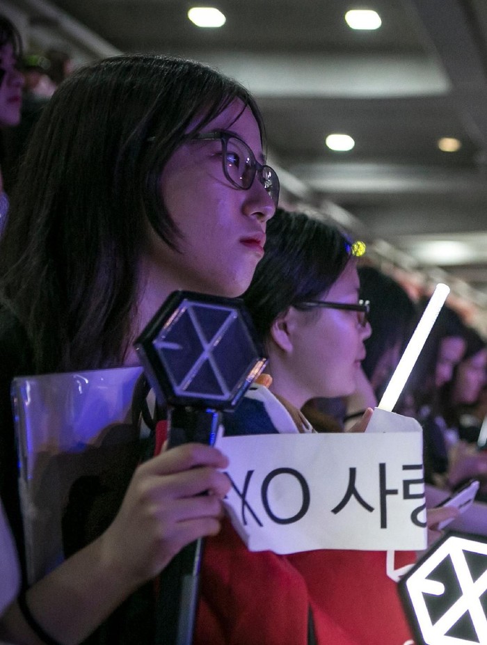 SUWON, SOUTH KOREA - JUNE 18:  A South Korean fan (L) of a boy band, Exo, (not shown) holds a banner as a K-Pop band perform on stage on June 18, 2016 in Suwon, South Korea.The particular concert was organized by the city government of Suwon, commemorating the 220th anniversary of Suwon-Hwaseong Fortress, a UNESCO heritage site. It featured 25 K-Pop idol groups and solo artists for two days: June 17 and 18, 2016, drawing more than 10,000 visitors. The South Korean government, both on a central and local level, try to boost tourism by sponsoring and directly organizing K-Pop concerts in big venues. The fans come from Korea as well as Japan, China, and Southeast Asia, as the popularity of K-pop had rapidly grown after it started in Japan in the early 2000s, and expanded its fan base to teenagers and young adults in China, Southeast Asia, and as far as Latin America.  (Photo by Jean Chung/Getty Images)